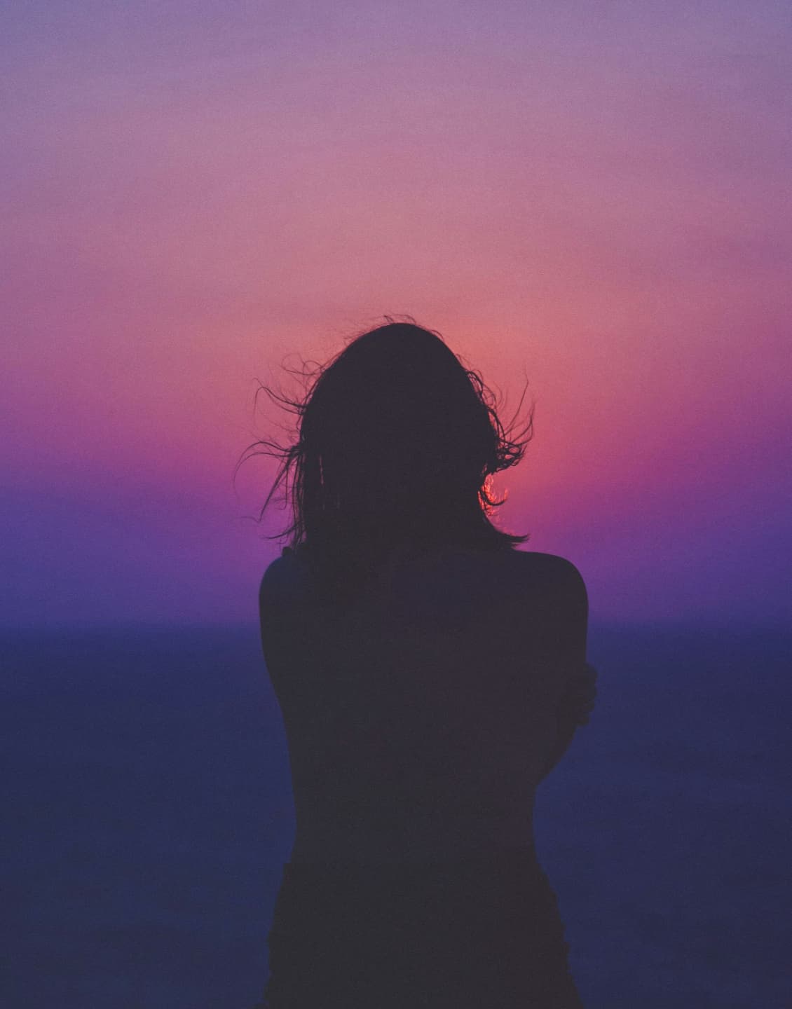 Silhouette of a person deep in thought against a sunset sky