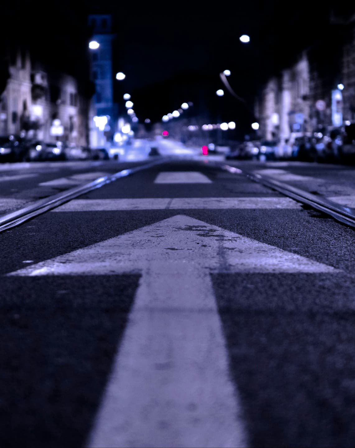 A white arrow road marking on a city street at night